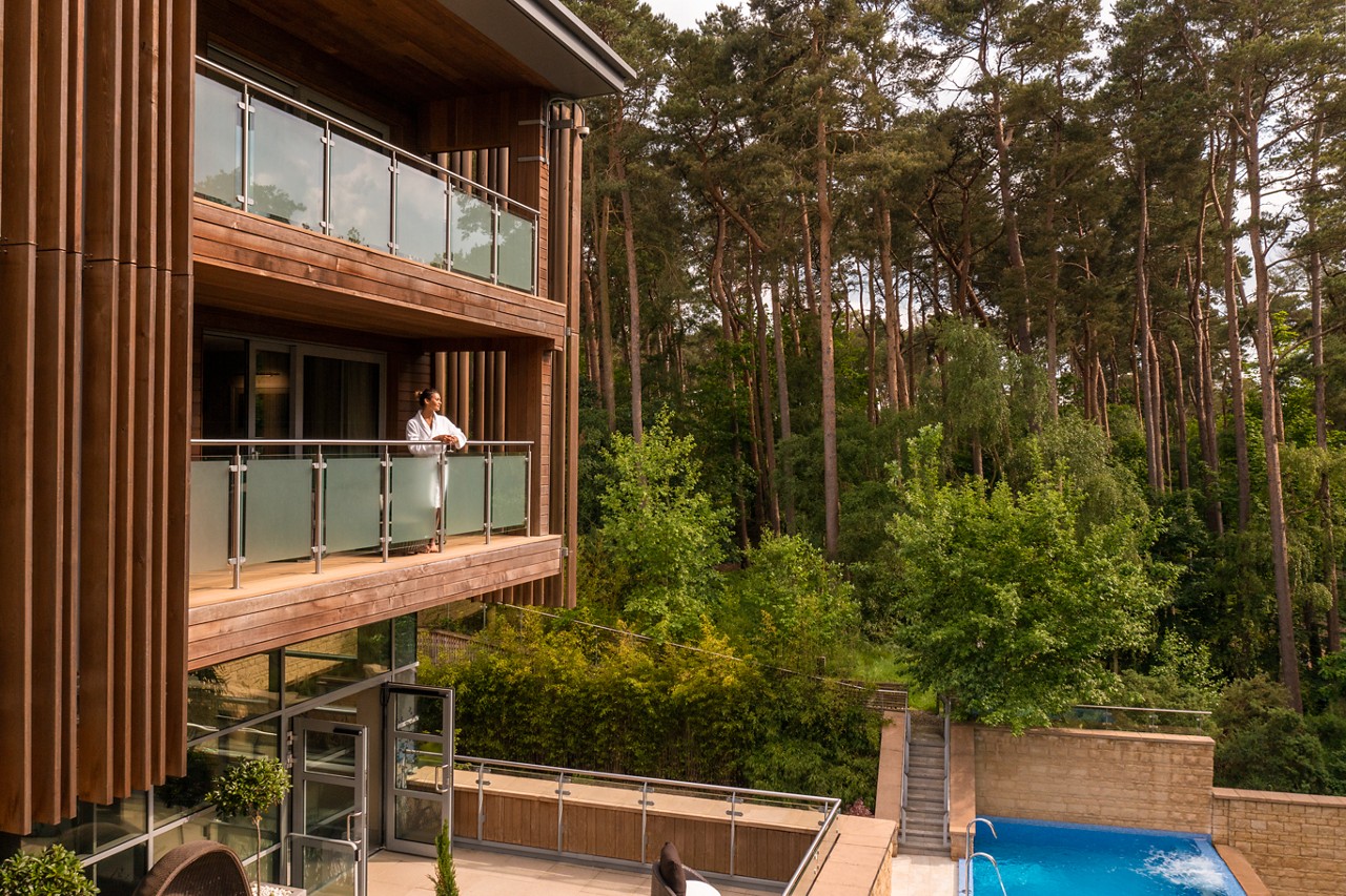 Woman standing on a Spa Suite balcony taking in the forest views.